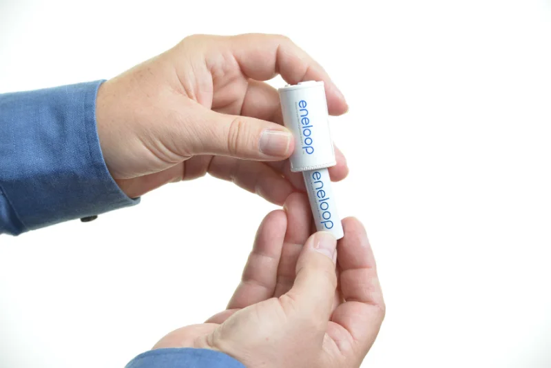 An eneloop AA going into a C adapter. The shell holds one cell, and the cell comes back out to charge.